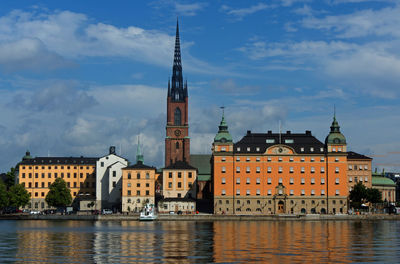 Buildings at waterfront against cloudy sky