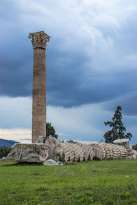 Low angle view of stone structure on field against cloudy sky