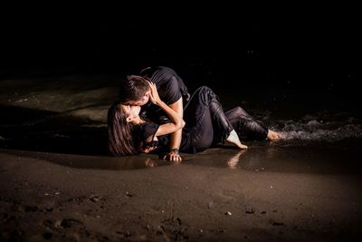 Rear view of couple sitting on land against black background