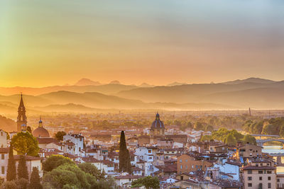 High angle view of city against silhouette mountains during sunset