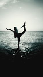 Silhouette of woman in sea at sunset