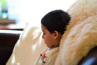 Profile view of boy sitting on sofa at home