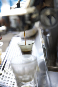 Close-up of espresso being poured by espresso machine into a small glass 