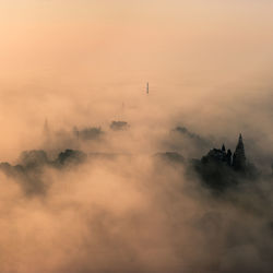 Scenic view of fog against sky at sunset