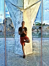 Full length portrait of young man in glass window