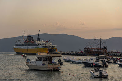 Fishing boats in sea against sky during sunset