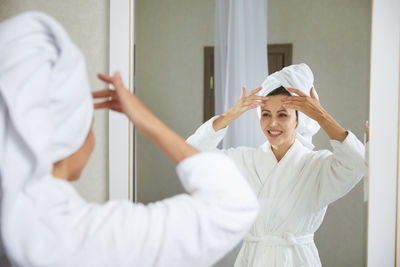 Young woman with arms raised standing in bathroom