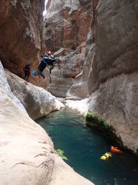 Man jumping in river amidst rock formations