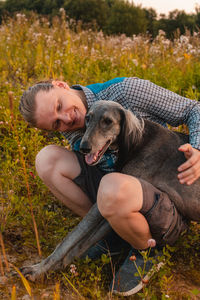 Young happy man hugs a dog outdoors. the owner spends time with his pet.