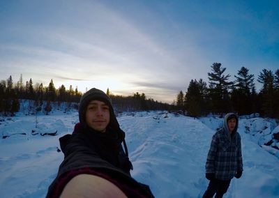 Portrait of man standing with friend on field during winter