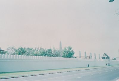 Road by buildings against sky