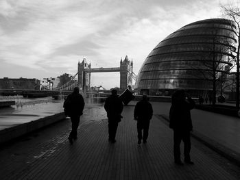 People on bridge against cloudy sky