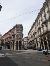 Street by buildings against sky in city