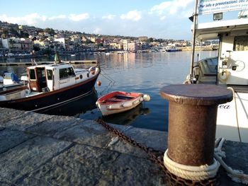 Boats moored at harbor against sky in city