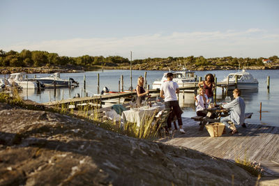 Young multi-ethnic friends enjoying summer at harbor against sky on sunny day