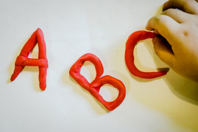 Cropped hand making alphabets with modelling clay on white table
