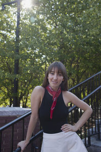 Portrait of a smiling young woman standing against trees