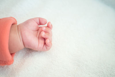 Low section of baby lying on bed