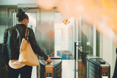 Rear view of businessman using id card at turnstile in office