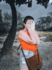 Midsection of man standing by tree on field