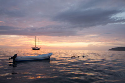 Boat sailing in sea against cloudy sky