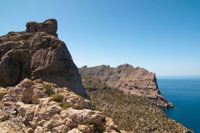 Rock formations in sea against clear sky