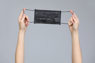Cropped hands of woman using smart phone against white background