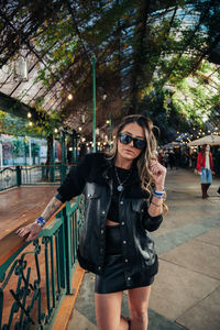 Portrait of young woman wearing sunglasses standing against plants
