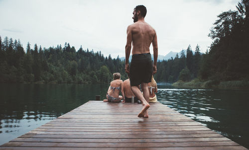 Rear view of men on pier over lake against sky