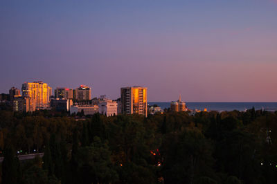Trees and buildings against sky during sunset