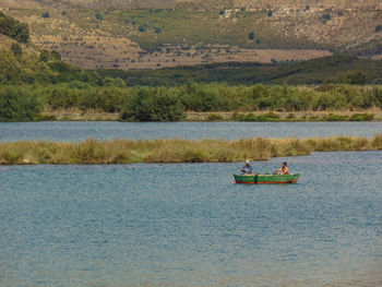 People in boat on lake against mountain