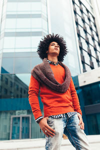 Young man looking away while standing on footpath