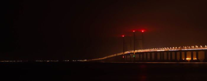 Illuminated bridge over river at night