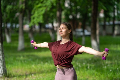 Young woman with arms raised standing on field