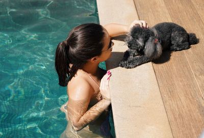 Rear view of woman sitting on swimming pool