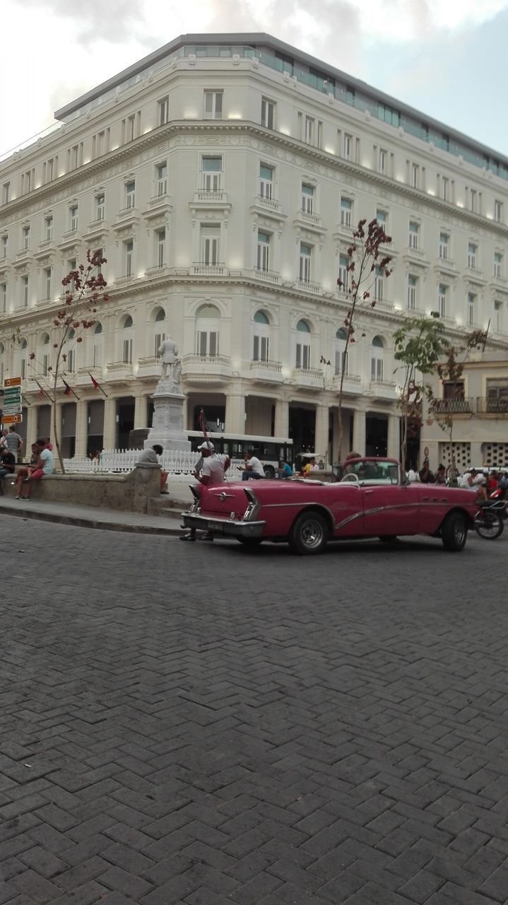 CARS ON ROAD BY BUILDING AGAINST SKY