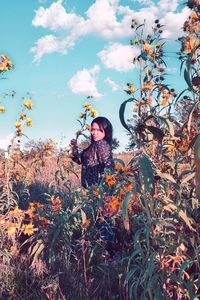 Woman standing by plants on land against sky