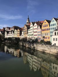 Buildings by river in town against sky