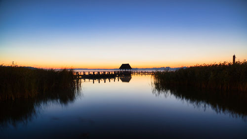 Scenic view of lake against clear sky during sunset