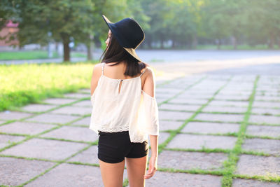 Rear view of woman standing on footpath