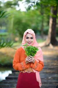 Portrait of a smiling young woman holding plant