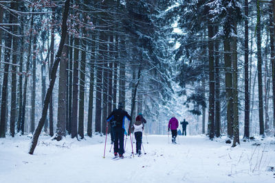 Unrecognizable children and adults skiing in the woods