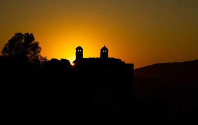 Silhouette building against orange sky