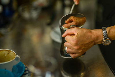 Hands of young adult caucasian female barista at work preparing