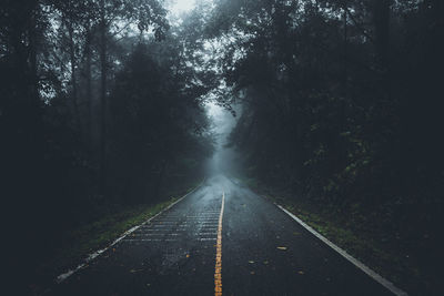 Empty road amidst trees against sky