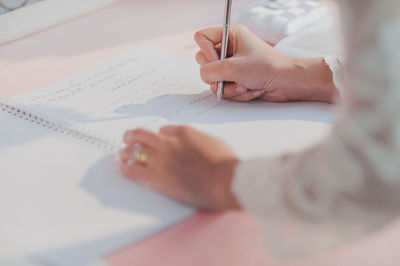 Close-up of bride signing paper on table