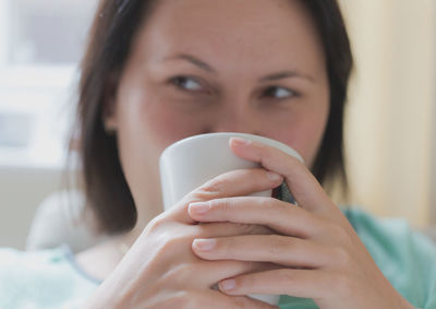 Close-up of young woman looking away while having coffee