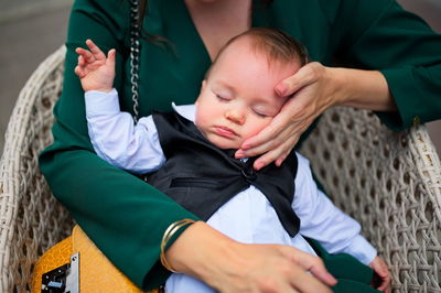 Little baby dressed for baptism sleeping in his mother lap