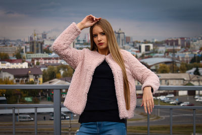 Portrait of young woman standing against cityscape in city