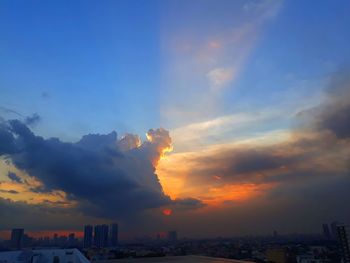 Smoke emitting from buildings against sky during sunset